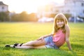 Young pretty child girl laying down on green grass lawn on warm summer day Royalty Free Stock Photo