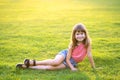 Young pretty child girl laying down on green grass lawn on warm summer day Royalty Free Stock Photo