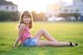 Young pretty child girl laying down on green grass lawn on warm summer day Royalty Free Stock Photo