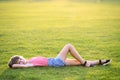 Young pretty child girl laying down on green grass lawn on warm summer day Royalty Free Stock Photo