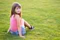 Young pretty child girl laying down on green grass lawn on warm summer day Royalty Free Stock Photo