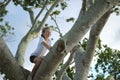 Young pretty child girl sitting relaxed between big branches of old tree on sunny summer day Royalty Free Stock Photo