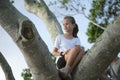 Young pretty child girl sitting relaxed between big branches of old tree on sunny summer day Royalty Free Stock Photo