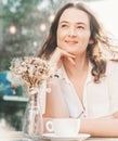 Young pretty curly woman drinking coffee tea in a street cafe on a summer day with a happy smile on her face Royalty Free Stock Photo