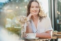 Young pretty curly woman drinking coffee tea in a street cafe on a summer day with a happy smile on her face Royalty Free Stock Photo