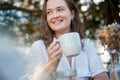 Young pretty curly woman drinking coffee tea in a street cafe on a summer day with a happy smile on her face Royalty Free Stock Photo