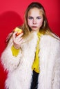 Young pretty emitonal posing teenage girl on bright red background eating apple, happy smiling lifestyle people concept Royalty Free Stock Photo