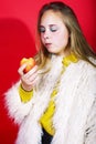 Young pretty emitonal posing teenage girl on bright red background eating apple, happy smiling lifestyle people concept Royalty Free Stock Photo