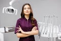 A young pretty female dentist is standing by the dental chair in the office with her arms crossed in front of her Royalty Free Stock Photo