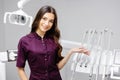 A young pretty female dentist is standing by the dental chair in the office with her arms crossed in front of her Royalty Free Stock Photo