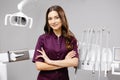 A young pretty female dentist is standing by the dental chair in the office with her arms crossed in front of her Royalty Free Stock Photo