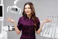 A young pretty female dentist is standing near the dental chair in the office, gesturing with her hands Royalty Free Stock Photo