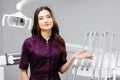 A young pretty female dentist is standing near the dental chair in the office, gesturing with her hands Royalty Free Stock Photo