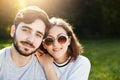 Young pretty female wearing trendy sunglasses having smile while leaning at shoulder of her bearded handsome boyfriend, posing tog Royalty Free Stock Photo