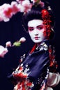 young pretty geisha in kimono with sakura and decoration on blac