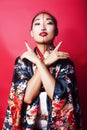 Young pretty geisha on red background posing in kimono, oriental concept Royalty Free Stock Photo