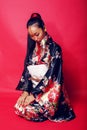 Young pretty geisha on red background posing in kimono, oriental people concept Royalty Free Stock Photo