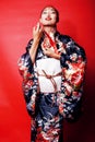 Young pretty geisha on red background posing in kimono, oriental people concept close up Royalty Free Stock Photo