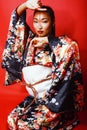 Young pretty geisha on red background posing in kimono, oriental Royalty Free Stock Photo