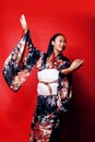 Young pretty geisha on red background posing in kimono, oriental people concept close up Royalty Free Stock Photo