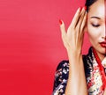 Young pretty geisha on red background posing in kimono, oriental Royalty Free Stock Photo