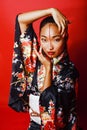 Young pretty geisha on red background posing in kimono, oriental Royalty Free Stock Photo