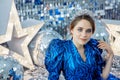 Young pretty girl in blue dress with new year decorations on the background