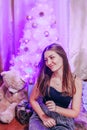 Young pretty girl with burning sparkler under christmas tree close-up