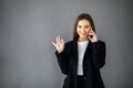 Young pretty girl in business style clothes stands on a gray background with a mobile phone in her hands. Business style Royalty Free Stock Photo