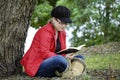 Young pretty girl with cheeky expression relaxing reading book in countryside