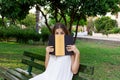 Young pretty girl is covering her face with a book because of feeling surprise and shock. Emotional funny woman is holding a book Royalty Free Stock Photo