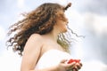 A Young Pretty Girl In The White Dress Standing Against Sky With Red Rose In The Hands.