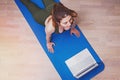 Young pretty girl doing yoga on the mat with her laptop near Royalty Free Stock Photo