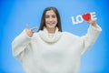 Young pretty girl dressed in white clothes. During this time it stands on a blue background. Holds a word of love in