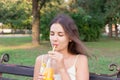 Young pretty girl is drinking lemonade from the bottle through the straw with a great pleasure Royalty Free Stock Photo