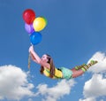 Young pretty girl fly on colorful balloons in the blue sky Royalty Free Stock Photo