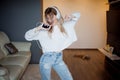 Young pretty girl in headphones with the phone. Listening to music, dancing and singing, indoors Royalty Free Stock Photo