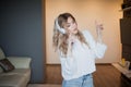 Young pretty girl in headphones with the phone. Listening to music, dancing and singing, indoors Royalty Free Stock Photo