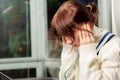 Young pretty girl in headphones sitting at a laptop learns a foreign language on the windowsill at the window