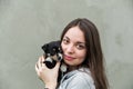 The young pretty girl with a little cute puppy. Grey background. Protection and assistance to animals concept