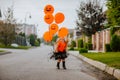 Girl playing on the street with pumpkin balloons while sunrise. Royalty Free Stock Photo