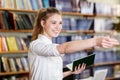 Young pretty girl posing at camera in the library. Education concept. Royalty Free Stock Photo