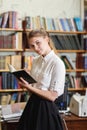 Young pretty girl posing at camera in the library. Education concept. Royalty Free Stock Photo