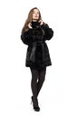 Young pretty girl posing in dark short mink fur coat, full height isolated on white background Royalty Free Stock Photo