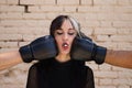 Young and pretty girl with a punkish tendency. She is being hit on each side of her face with boxing gloves while holding a jelly