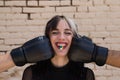 Young and pretty girl with a punkish tendency. She is being hit on each side of her face with boxing gloves while holding a jelly Royalty Free Stock Photo