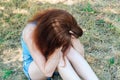 A young pretty girl with red hair is holding her head, it became bad on the street, very sad Royalty Free Stock Photo