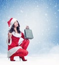 Young pretty girl in a red Santa suit holds a package with a gift in her hand, on a light blue background with snow Royalty Free Stock Photo