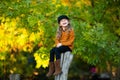 Young girl sitting up the wooden stump and smiling. Autumn background. Copy space Royalty Free Stock Photo