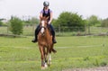 Young pretty girl riding a horse with backlit leaves behind in s